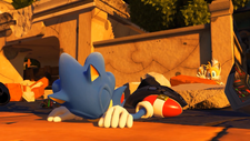 In-game screenshot of a Sonic Forces cutscene set in the City. Sonic can be seen lying in defeat, seemingly unconscious. Tails is shown hiding behind some debris nearby, with a concerned expression and extending his right arm towards Sonic.